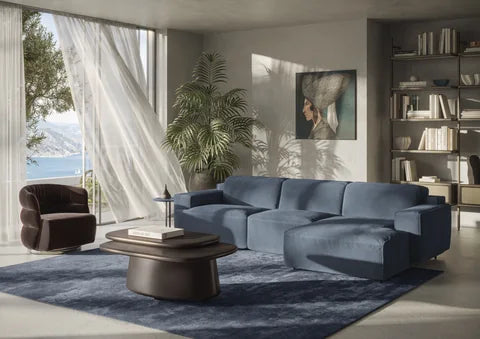 Natuzzi Italia Iago sofa in blue upholstery with a chaise, in a sunlit room with wooden tables