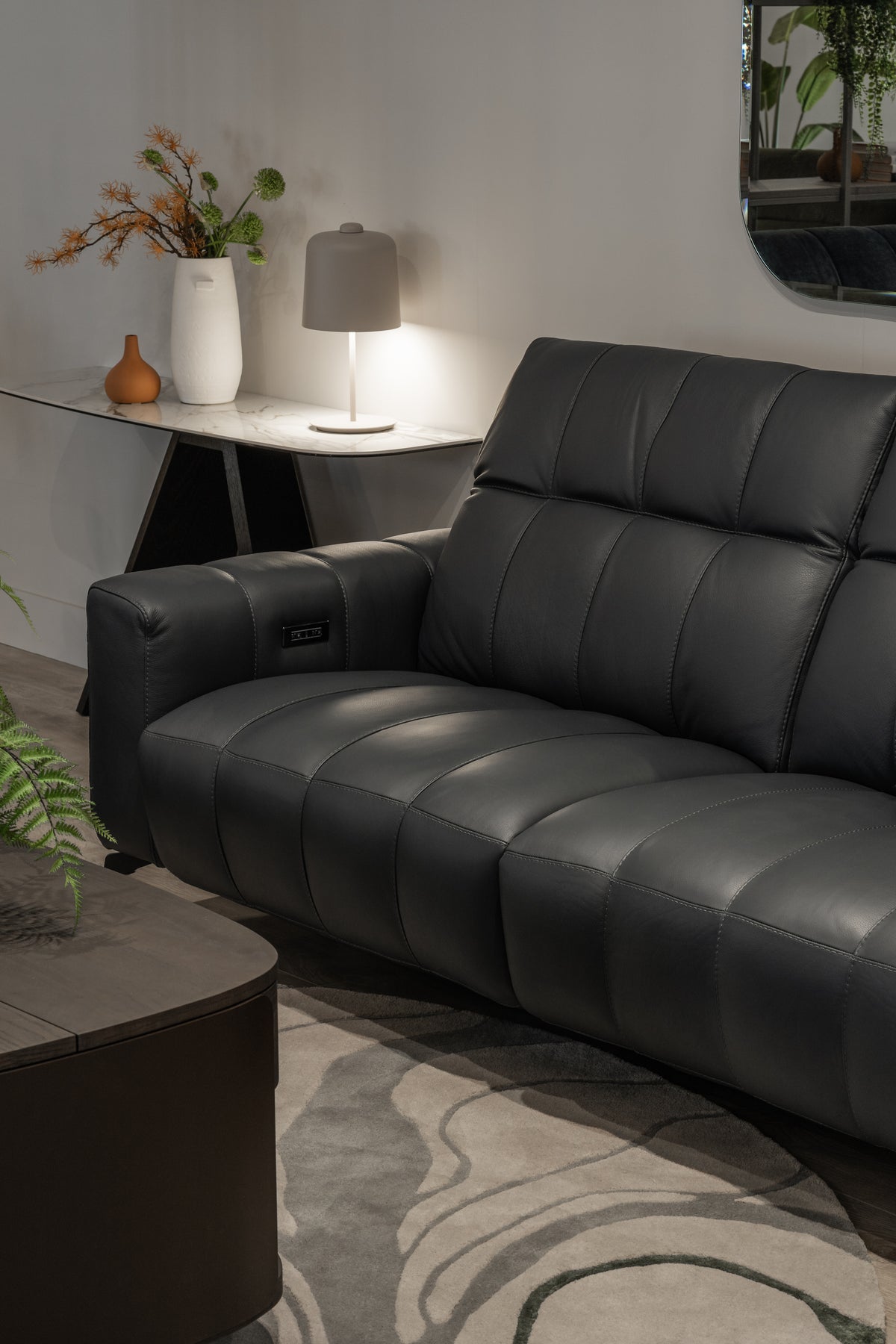 Close-up of the actual Portento Madison Blue Night leather power sofa, showing stitched upholstery and the reclining controls.