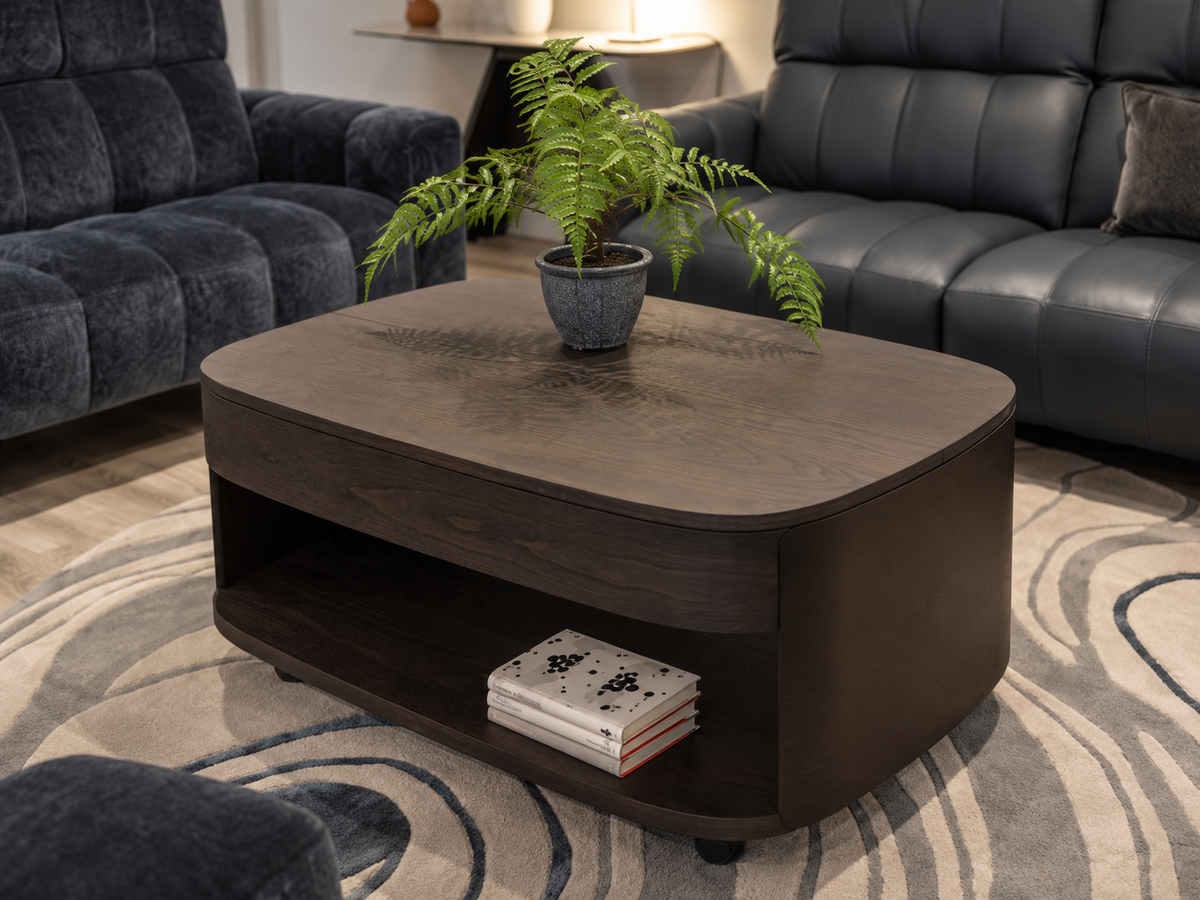 Vega brown ash coffee table in the Fultons showroom, showing wood grain, curved ends and open shelf; plant and books excluded.