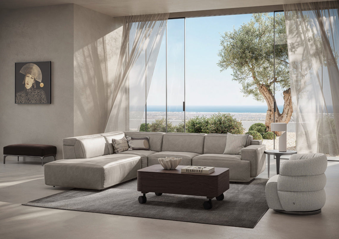 Pale living room seating with a dark coffee table, large windows and a sea view.