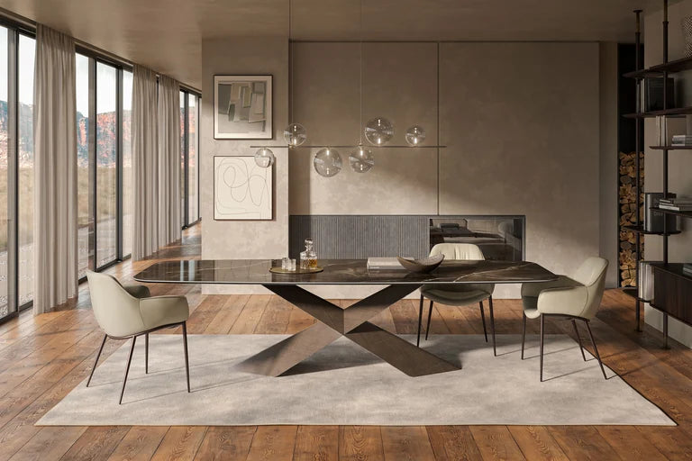 Cattelan Italia Tyron dining table with a sculptural cross base in a warm room beside tall windows.