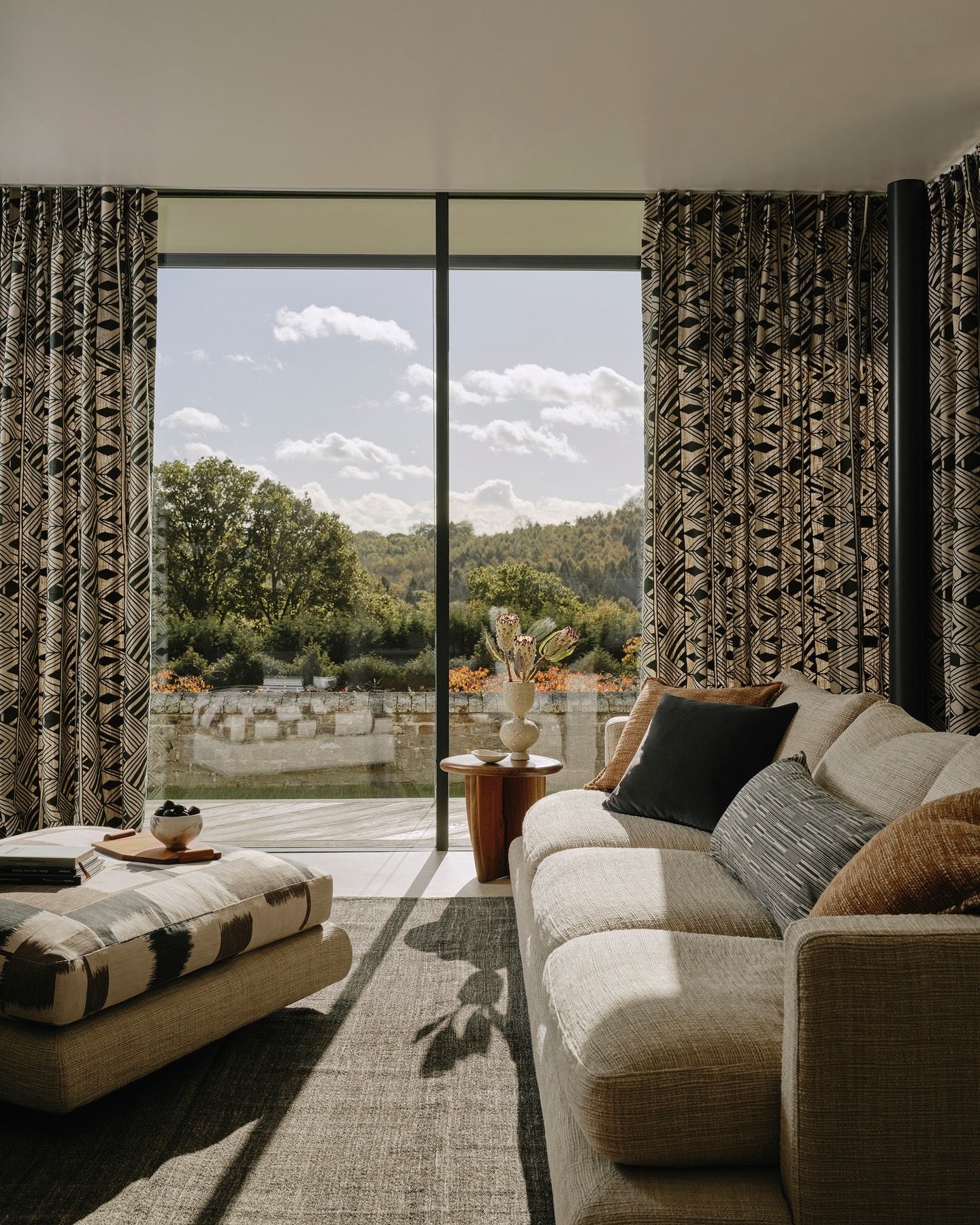 Patterned Larsen curtains framing a full-height window in a living room